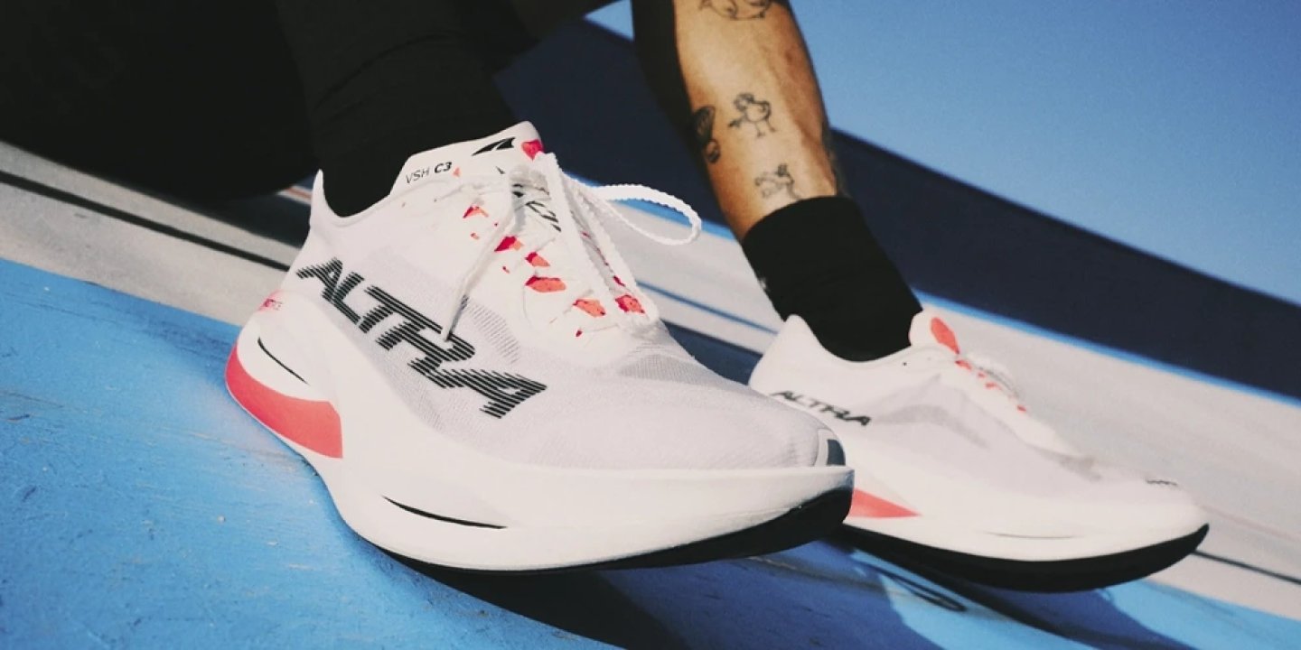 Altra Vanish Carbon 3 running shoes in white and coral colorway worn on a blue track surface
