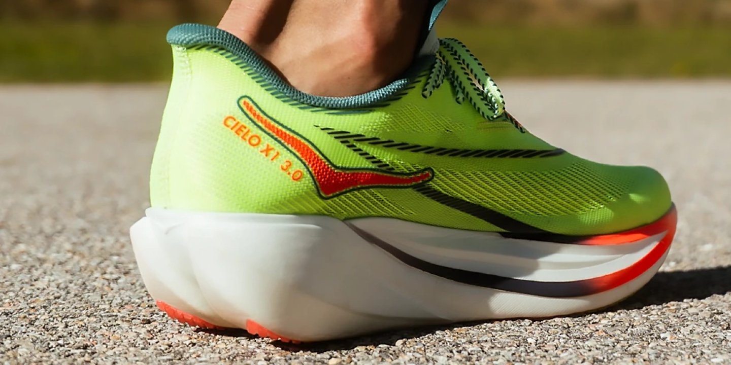 Side rear view of Mizuno Cielo X1 3.0 running shoe in lime green with orange logo and thick white midsole on road surface