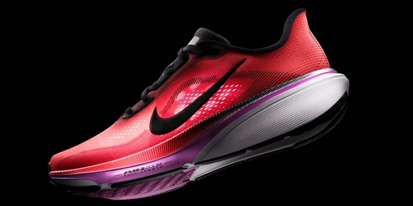Nike Air Zoom running shoe with red mesh upper, black Swoosh logo, purple and white full-length Air Zoom midsole.