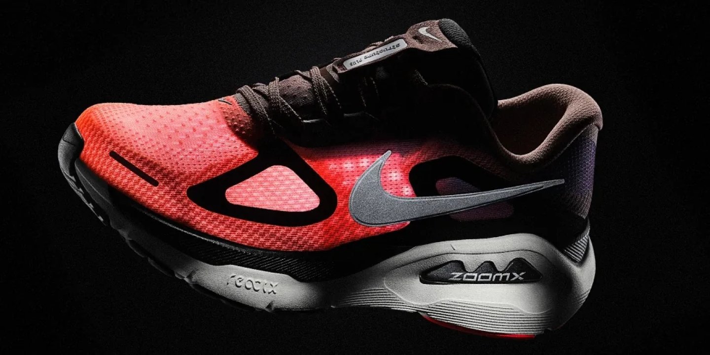Nike ZoomX running shoe with red mesh upper, black overlays, silver Swoosh, and ZoomX foam midsole on dark background.