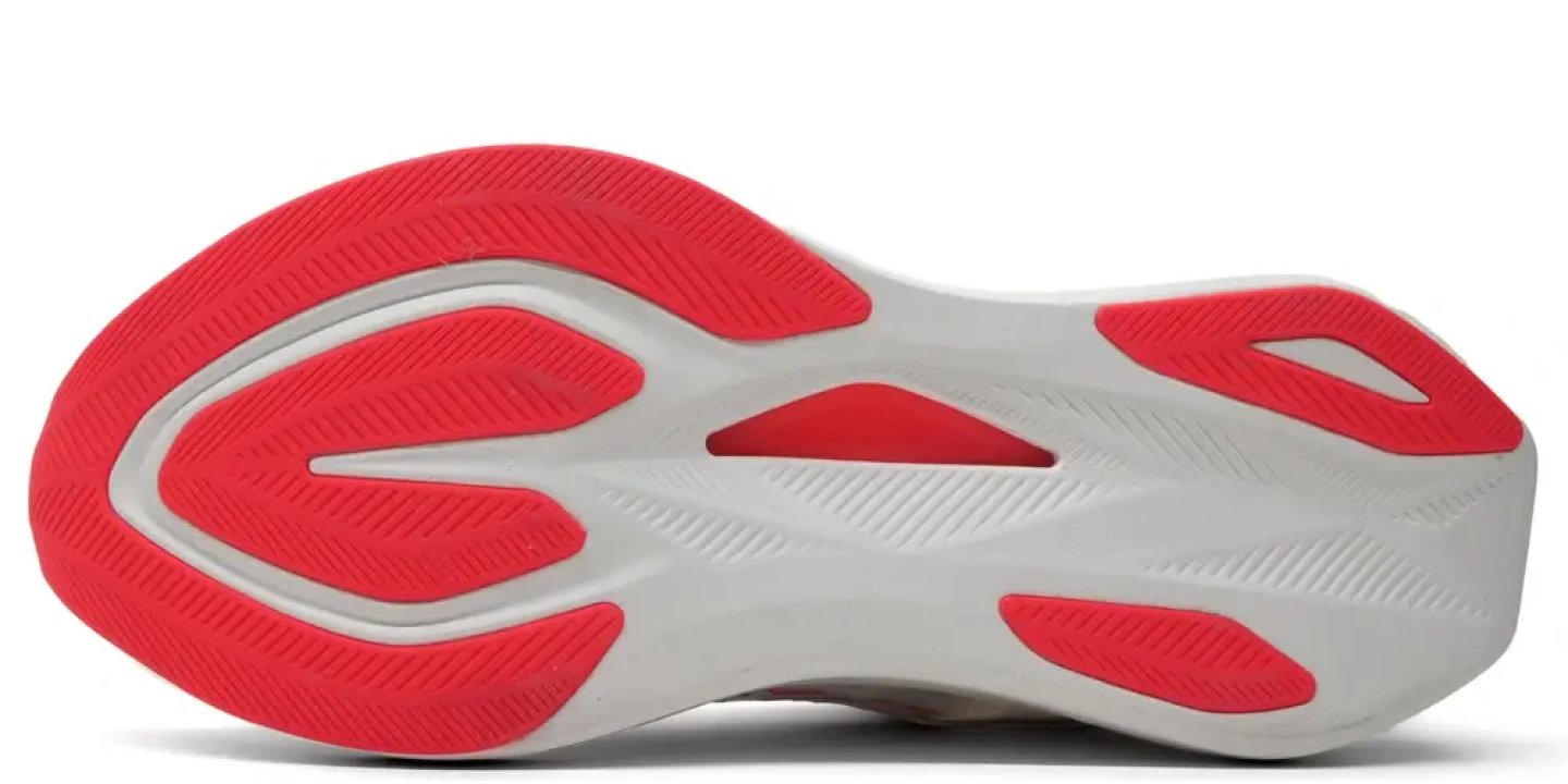 Bottom view of Asics running shoe outsole with red rubber traction pads and white foam midsole on white background