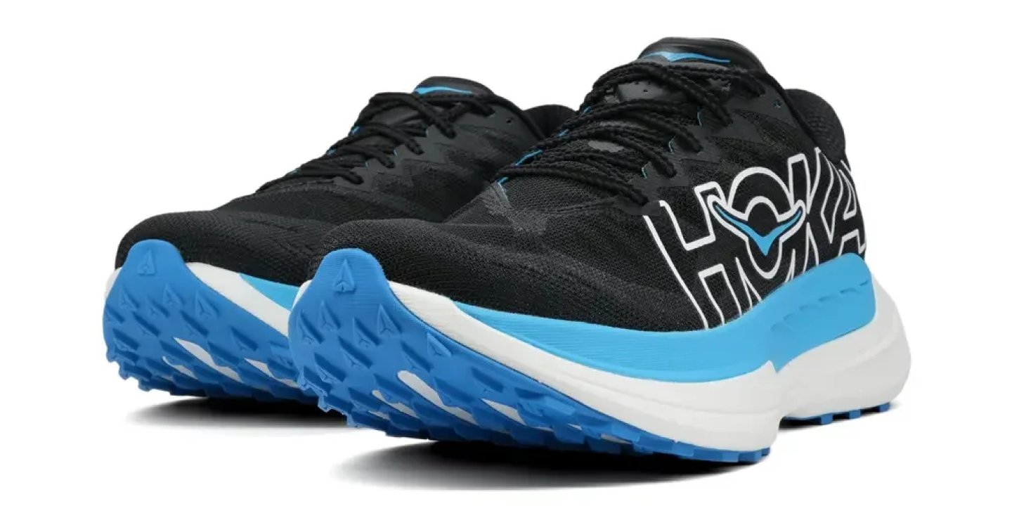 Hoka trail running shoes in black with blue midsole and aggressive lug outsole, shown as a pair.
