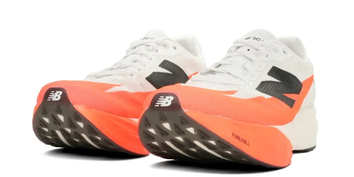 New Balance FuelCell SC running shoes in white with orange midsole and black logo, shown as a pair from rear angle.