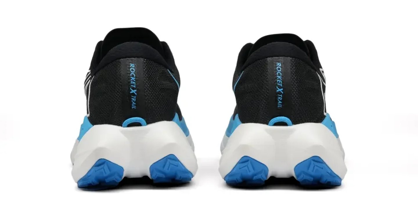 Rear view of New Balance Rocket X Trail shoes in black with white midsole and blue outsole heel pods.
