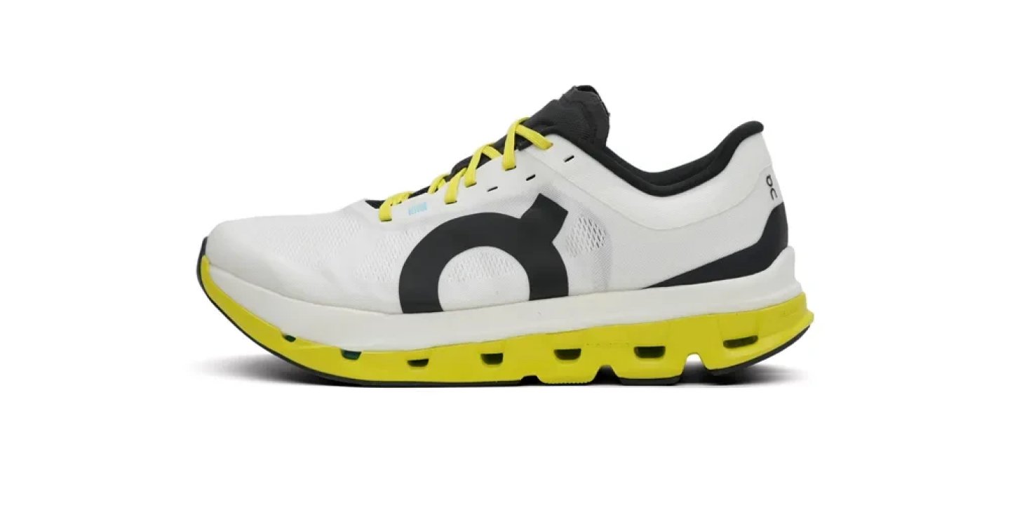 On Cloudmonster running shoe in white and black upper with yellow CloudTec midsole and yellow laces, lateral view