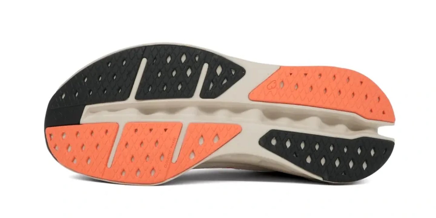 Bottom view of On running shoe outsole showing CloudTec perforated rubber pads in orange and dark grey on cream midsole