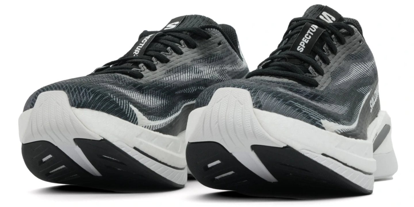 Pair of Salomon Spectur running shoes in black and white, rear three-quarter view showing knit upper and thick midsole