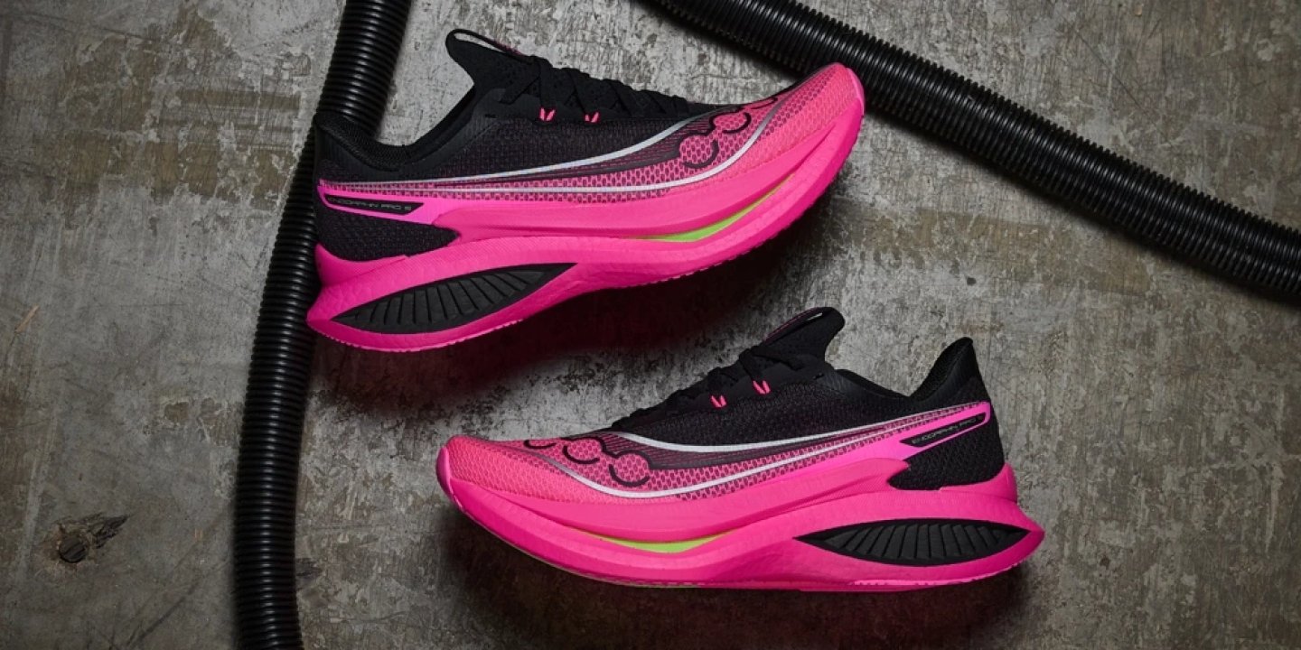 Pair of Saucony Endorphin Pro running shoes in black and vivid pink with carbon plate midsole on grey surface